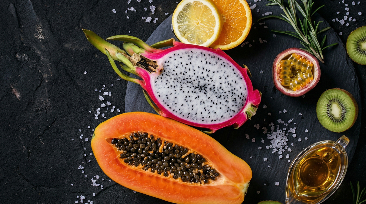 Papaya, Drachenfrucht, Kiwi und Passionsfrucht  auf einer Steinplatte serviert