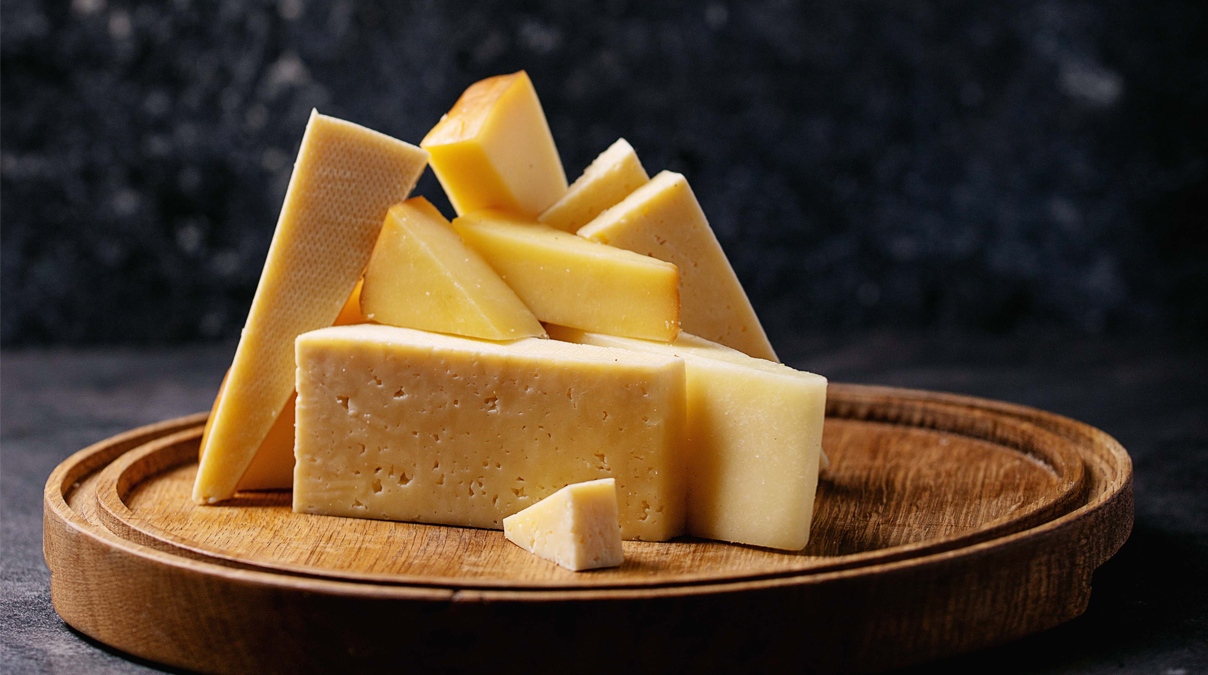 Geschnittener Käse auf einem runden Holzbrett