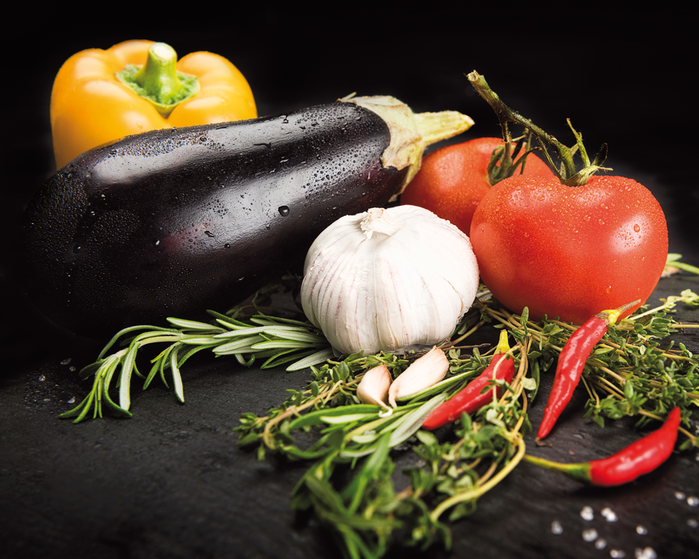 Platte mit frischen Tomaten, Melanzani, Paprika, Knoblauch, Chili und frischen Kräutern